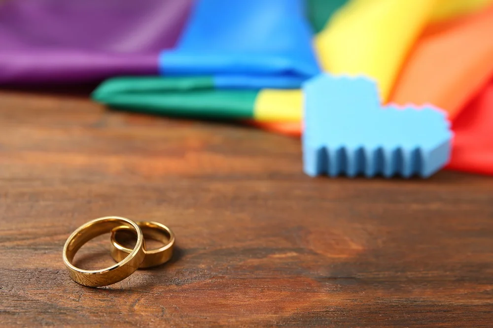 wedding rings and rainbow flag on wooden table ga 2026 03 05 11 42 35 utc