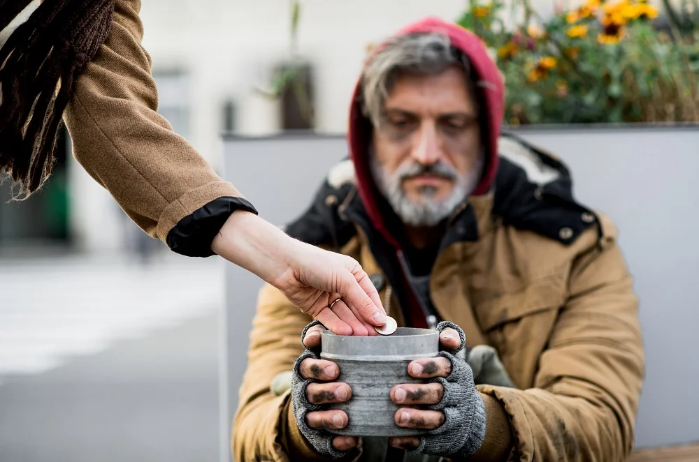 unrecognizable woman giving money to homeless begg 2026 03 10 02 08 19 utc